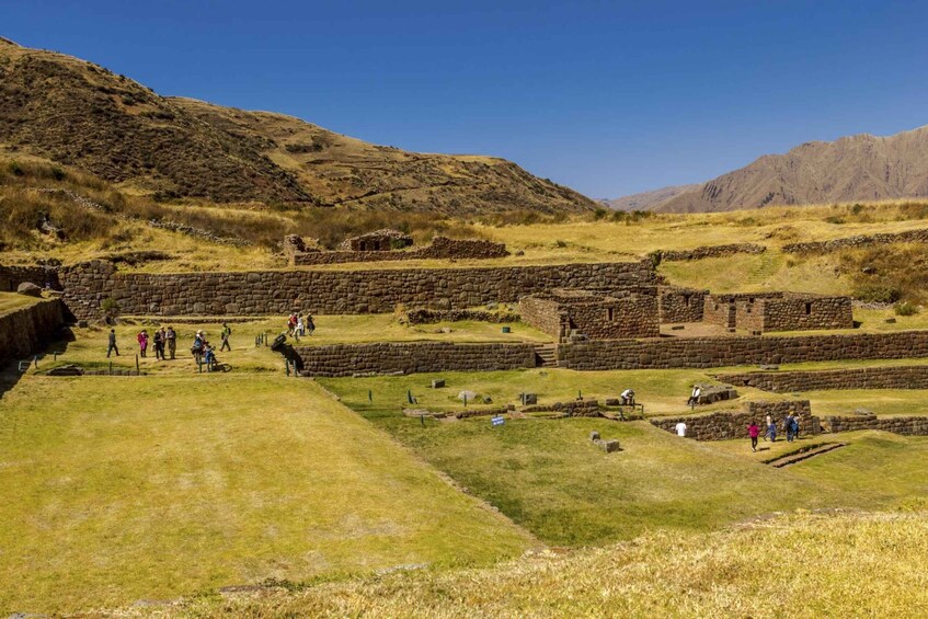 Ancient stone ruins with people walking around. 4
