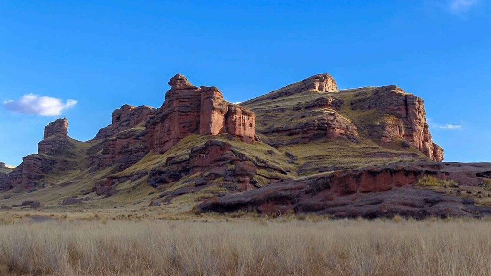 A landscape with red rock formations and grassy plains under a clear blue sky. 1