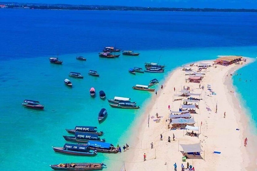 A beach with several boats anchored near the shore and people enjoying the beach. 2