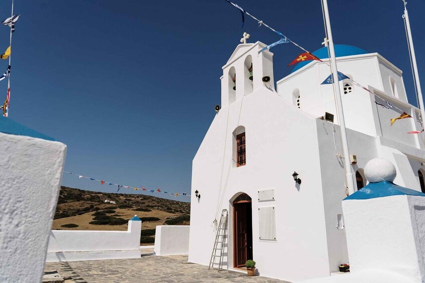 A white church with a blue dome, a ladder, and flags. 2
