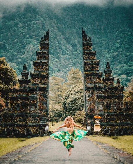 A woman jumping in front of a temple with a forest in the background. 5