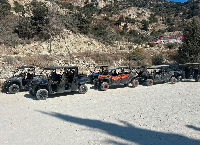 Off-road vehicles parked on a gravel surface with a rocky hillside and sparse vegetation in the background. 5