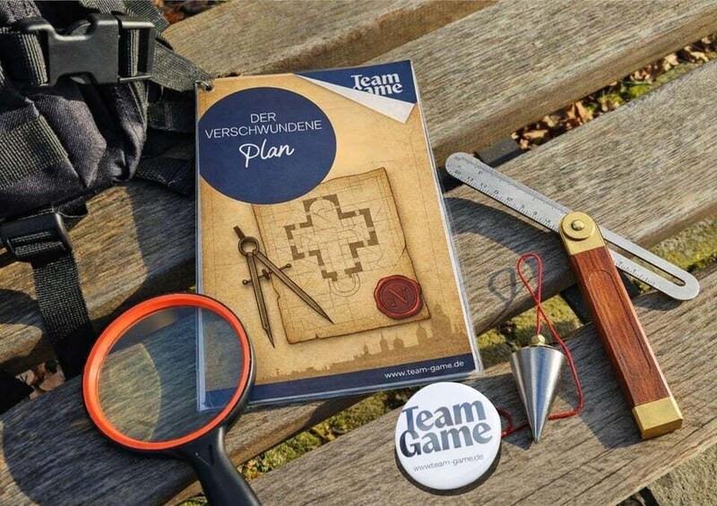 A board game titled 'Team Game' with a map and compass on a wooden surface. 2