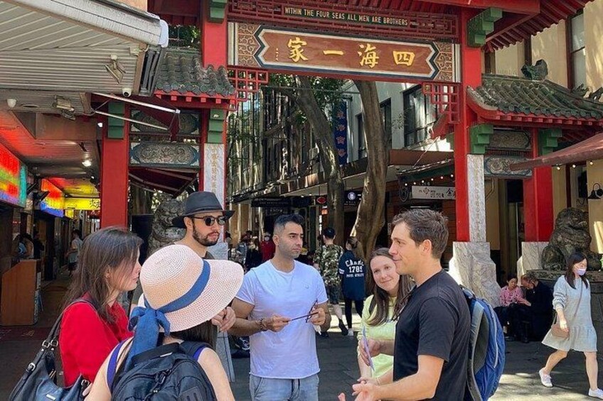 A traditional Chinese gate with intricate designs and characters, surrounded by a busy street with pedestrians. 5