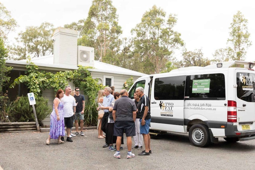 A group of people standing in front of a white van with the text "TWO FAT BLOKES" on it. 3