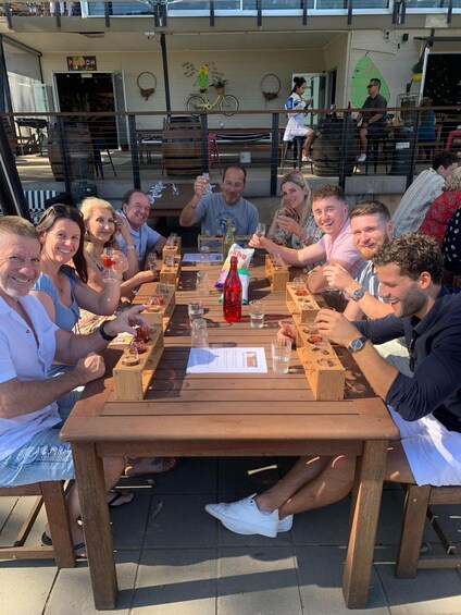 A group of people toasting at a wooden table outdoors. 2