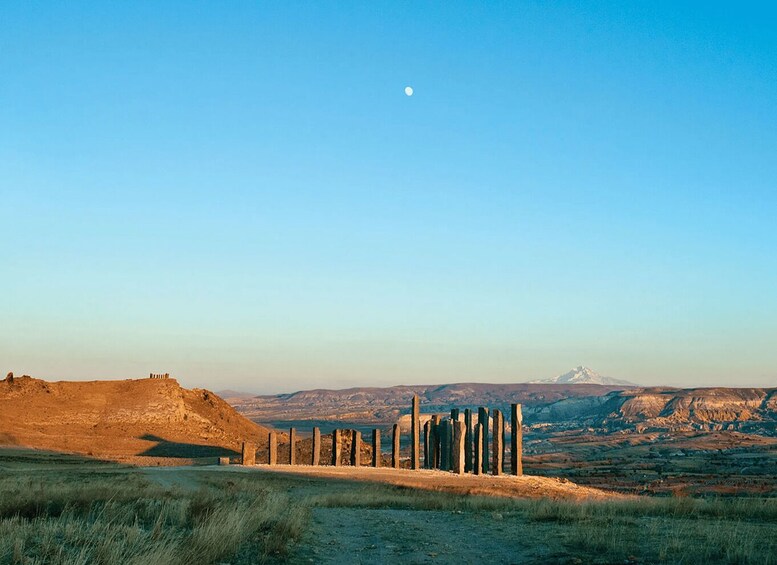 A landscape with a stone wall, a hill, and a mountain in the distance under a clear sky. 3