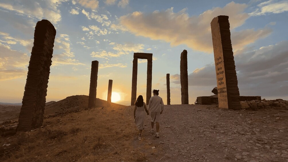 Ancient stone pillars and a doorway in a desert landscape at sunset. 2