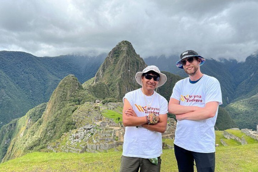 Two people standing in front of Machu Picchu with mountains in the background. 5