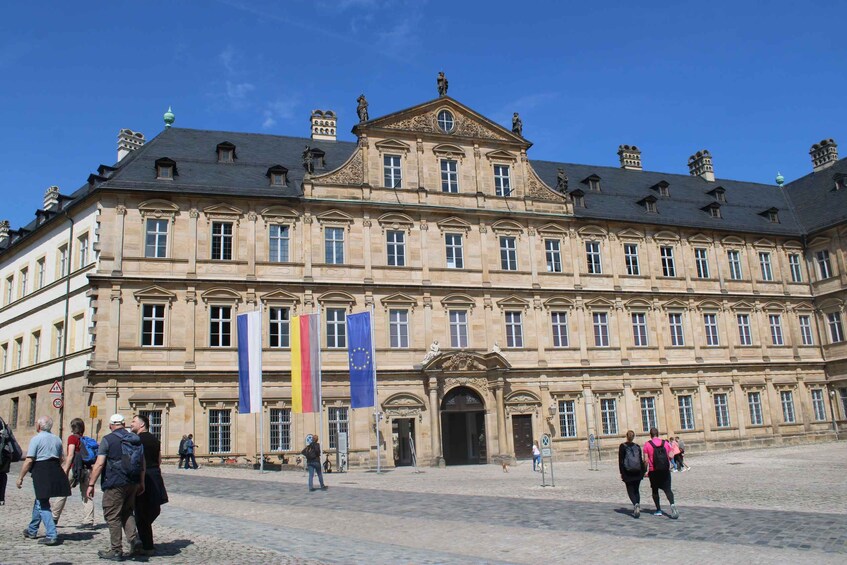 A historic building with classical architecture, multiple flags, and a cobblestone courtyard. 4