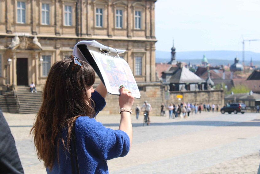 A person holding a map in an outdoor setting with historic buildings in the background. 5