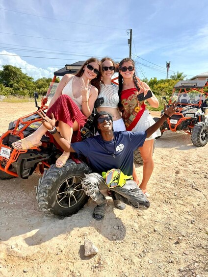 A group of people posing with off-road vehicles on a dirt road. 4