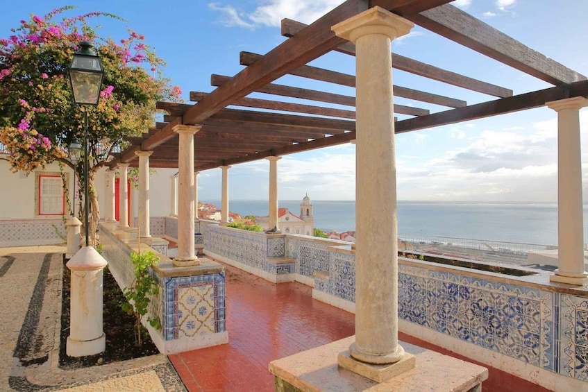 A coastal promenade with tiled railings, wooden pergola, and a view of the sea. 3