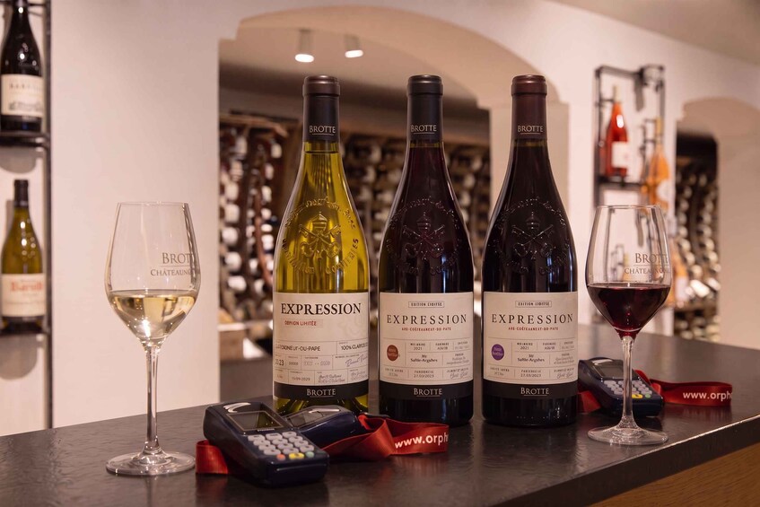 Four bottles of wine and two glasses on a bar counter. 1