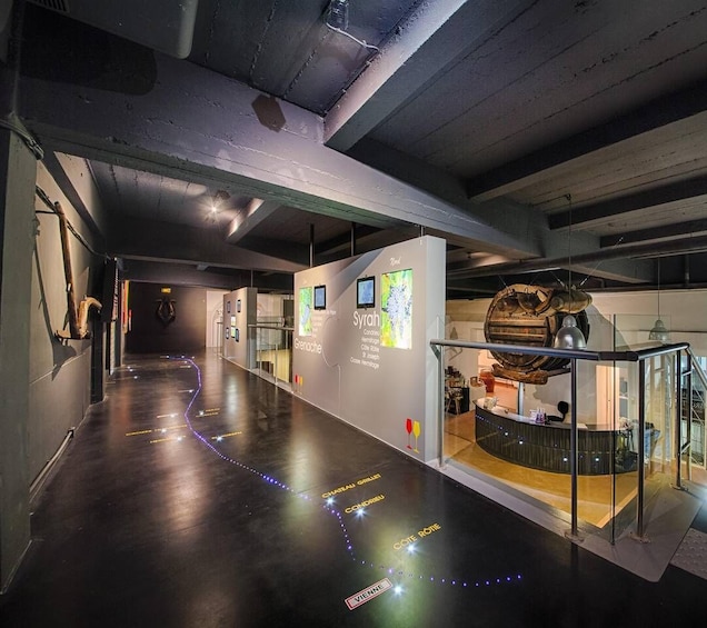 A modern interior space with a curved counter, illuminated signage, and a wooden barrel sculpture. 5