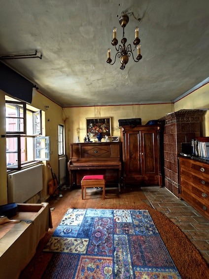A room with a piano, a rug, a chandelier, and a window. 3