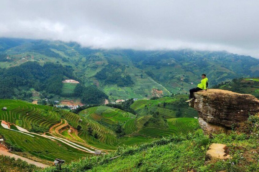 A person sitting on a rock overlooking terraced fields and a valley. 3