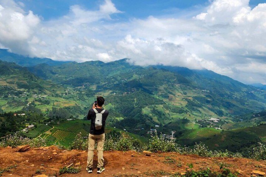 A person taking a photo of a mountainous landscape with fields and small buildings. 4
