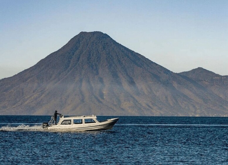 A boat on calm water with a mountain in the background. 1