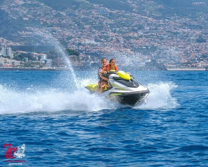 A jet ski with two people on it, creating a large splash in the water. 5