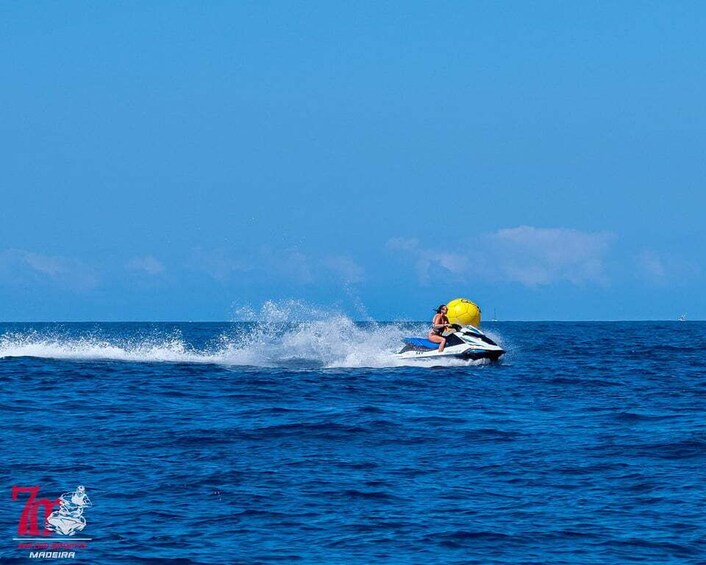 A person jet-skiing on a clear blue sea with a yellow helmet. 2