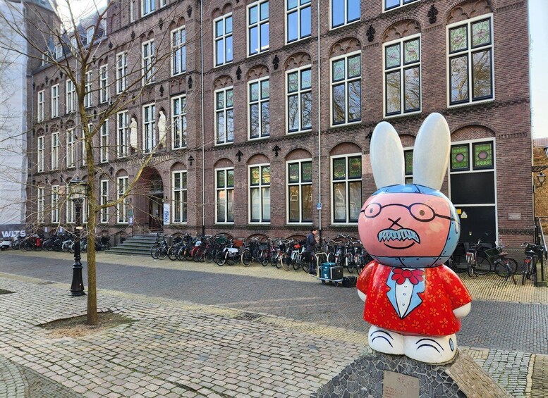 A large cartoon rabbit statue in front of a brick building with many windows. 3