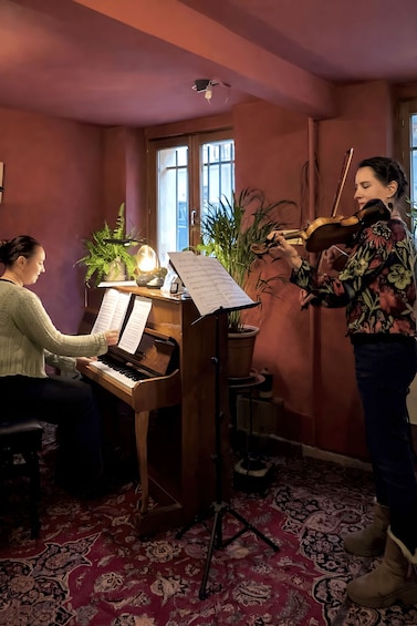 Eine Person spielt Violine neben einem Klavier mit Notenblättern. 2