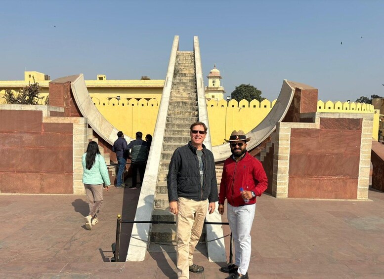 A group of people standing in front of a historical monument with a staircase leading up to a tower. 2