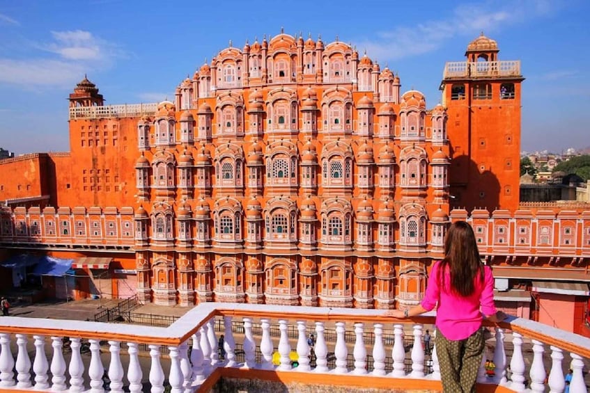 A large, ornate building with intricate architectural details and a balcony with white balustrades. 1