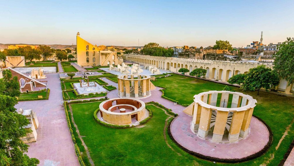 A historic site with circular structures, a large yellow building, and a long corridor with arches. 5