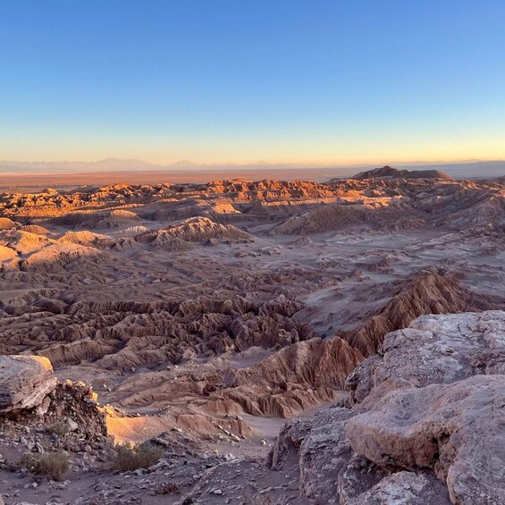 A rugged desert landscape with eroded hills and rocky terrain. 1