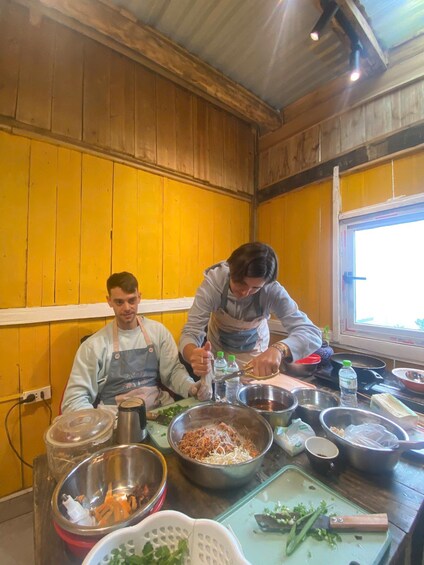 Two people cooking in a kitchen with wooden walls and a window. 5