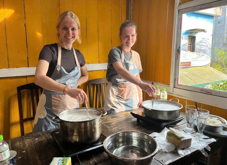 Two people cooking in a rustic kitchen with wooden walls and a window overlooking a mountainous landscape. 5