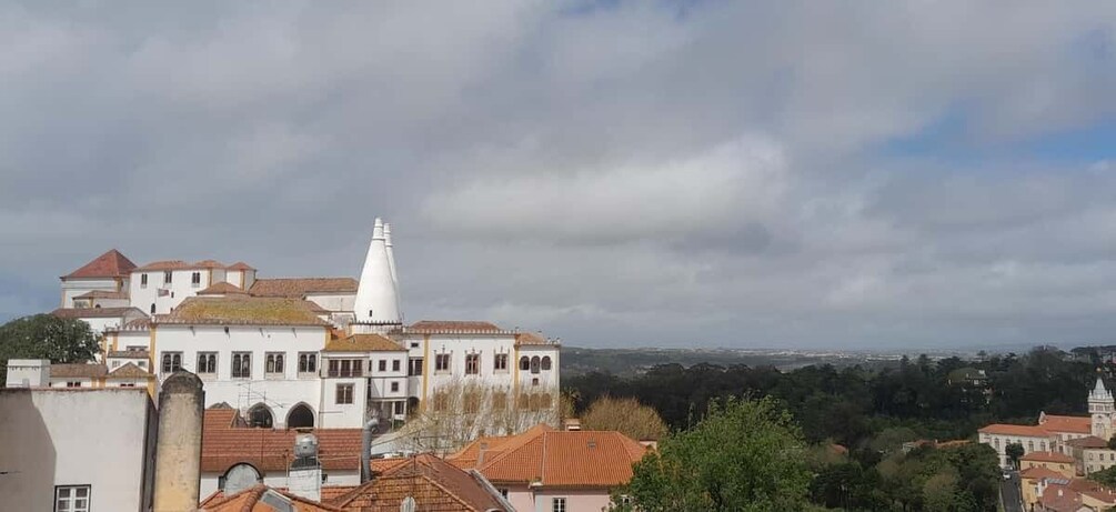 A coastal town with historic buildings, a prominent white tower, and a view of the sea. 5
