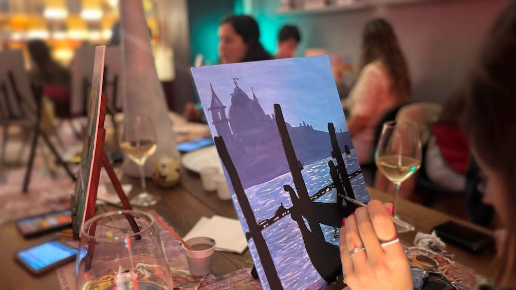 A person holding a painting of a castle by the sea. 5
