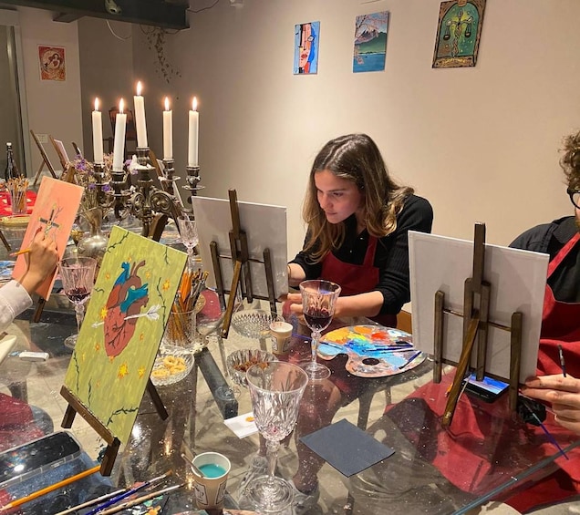 A person painting at a table with easels, paint palettes, and art supplies. 4