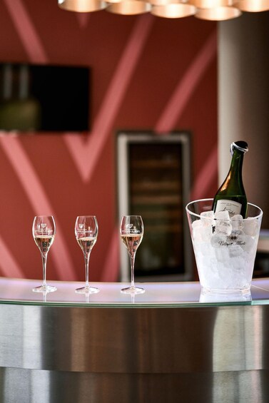 Three wine glasses on a bar counter with a bottle of champagne in a bucket of ice. 2