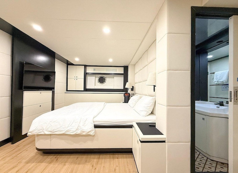 A modern bedroom with a bed, bedside tables, a mirror, and a bathroom visible through an open door. 5