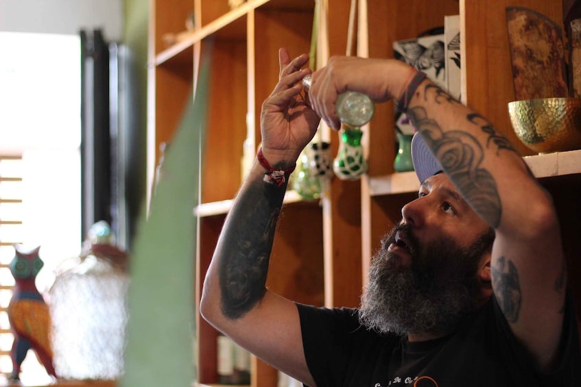 A person with tattoos on their arms holding a glass. 2
