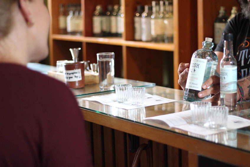 A person holding two bottles of whiskey at a bar. 3