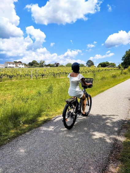 A person riding a bicycle on a paved path through a vineyard. 1