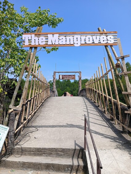 A bamboo bridge leading to The Mangroves entrance with a welcome sign. 5