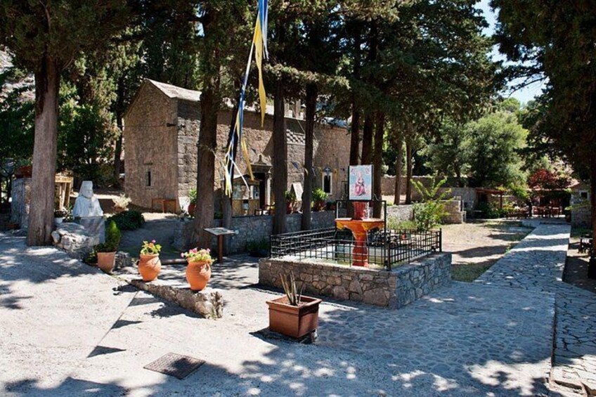A courtyard with stone buildings, potted plants, and a fountain. 2