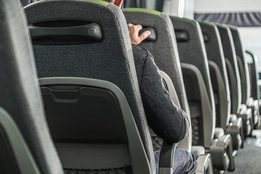 Rows of airplane seats with a person sitting in the middle row. 4