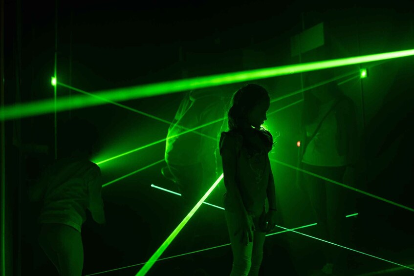 A person standing in a dimly lit room with green laser lights. 4