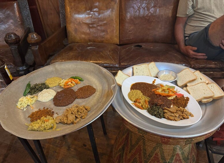 Two plates of Ethiopian cuisine on a table with a woven tablecloth. 1