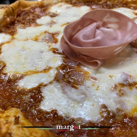 A pizza with melted cheese and a dollop of pink sauce on top. 5