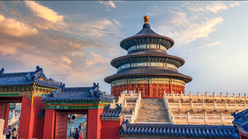 A traditional Chinese pagoda with intricate blue and gold roof tiles, surrounded by red walls and a stone staircase leading up to it. 5