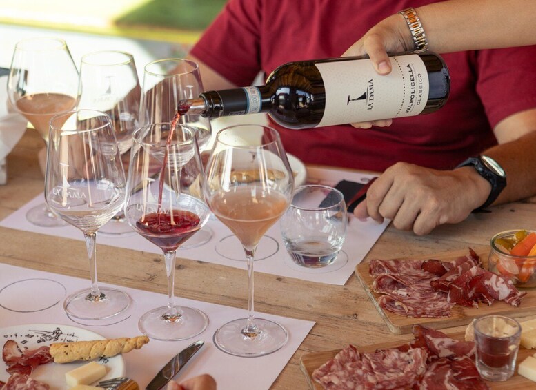 A person pouring wine into glasses on a table with food and cheese. 3
