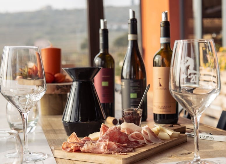 A table with wine bottles, glasses, and a charcuterie board with meats and cheese. 1